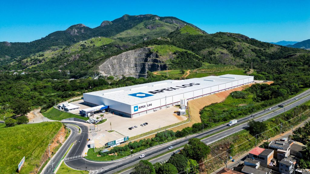 Vista aérea do galpão logístico da Apex Partners na Serra (ES), projetado em meio à vegetação com acesso direto à rodovia.
