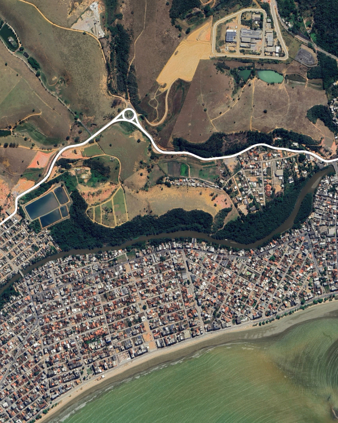 Vista aérea do sistema viário implantado em Piúma, ES, evidenciando novas vias com infraestrutura completa de drenagem, pavimentação e sinalização